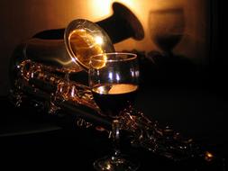 a glass of wine and a saxophone in the dark