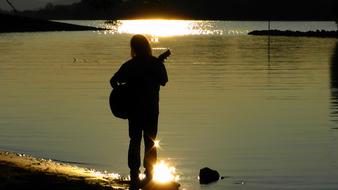 guitarist on the lake at sunset