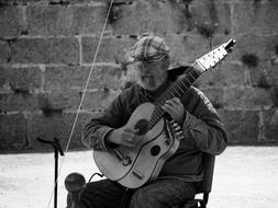 Monochrome picture of old guitarist playing outdoor