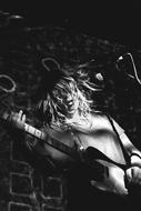 young long haired man plays guitar on stage