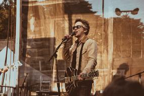 photo of a guitarist standing in front of a microphone
