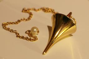 Beautiful, shiny gold pendulum on the gold chain, with the pearl