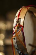 Beautiful tambourine with red rope, for pizzica, at blurred background