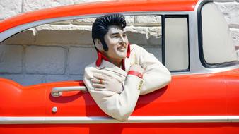 Figure of smiling Elvis Presley in red, retro car