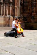 street musician with cello on the square in front of the cathedral in strasbourg