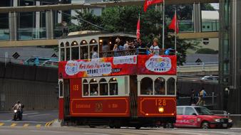 People, on the colorful and beautiful tram in HongKong, among the other vehicles