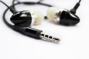 Black shiny earphones on the white surface