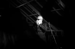 man plays mouth organ on stage, black and white