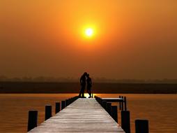 Couple on pier on Lake at Sunset