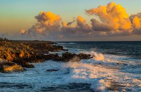 photo of sea waves and rocky shelter against the background of the evening cloudy sky