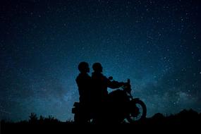 silhouettes of motorcyclists against the background of the starry sky