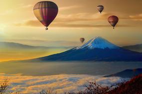 panorama of flying hot air balloons against a snowy mountain