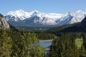 lake in green valley in front of scenic snow capped Mountains