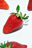 Close-up of the beautiful, shiny, ripe, red strawberries with green leaves, at white background