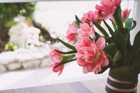a bouquet of pink flowers in a vase on the windowsill