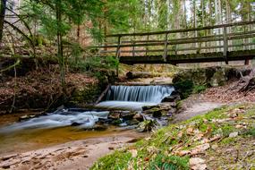 Beautiful river waterfall under a bridge among the plants in the forest