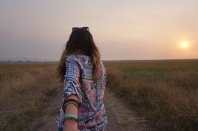 girl walking along the road during sunset