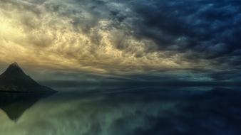 scenic clouds and rock mirroring on calm Ocean at Sunset