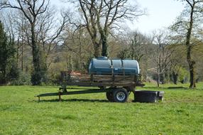 Tank on the wheels on the beautiful, green field, among the trees