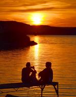 Silhouettes of the people, sitting on the bench, near the beautiful Lake Balaton, in Hungary, at colorful and beautiful sunset