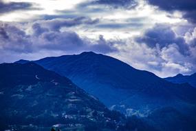 Beautiful landscape of the mountains, in blue colors, under the cloudy sky, at beautiful sunrise