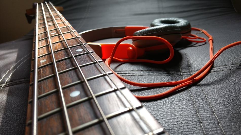 Headphones and neck of guitar on black leather