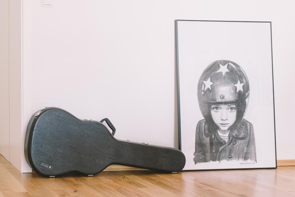 Black, hard guitar case, near the painting of the child, in the helmet with stars