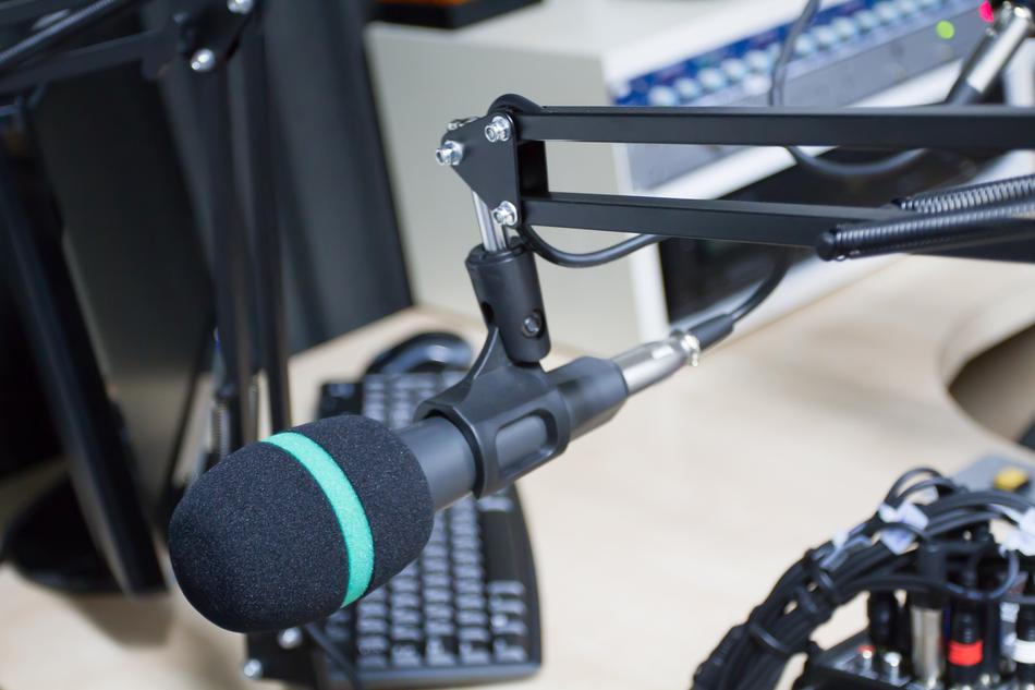 Black and turquoise microphone, near the black monitor with the black keyboard in the recording studio