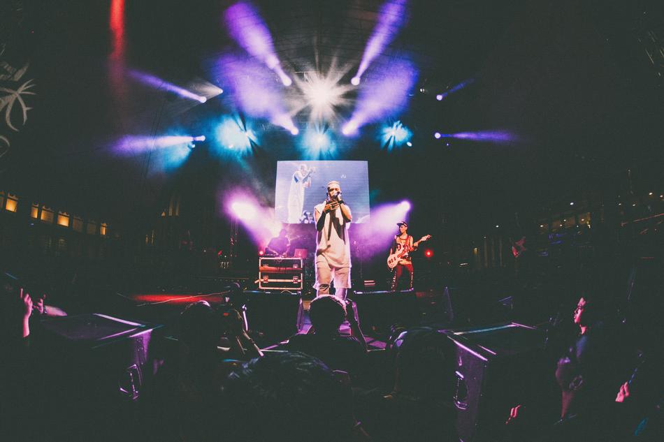 young male Singer on stage in front of crowd at night