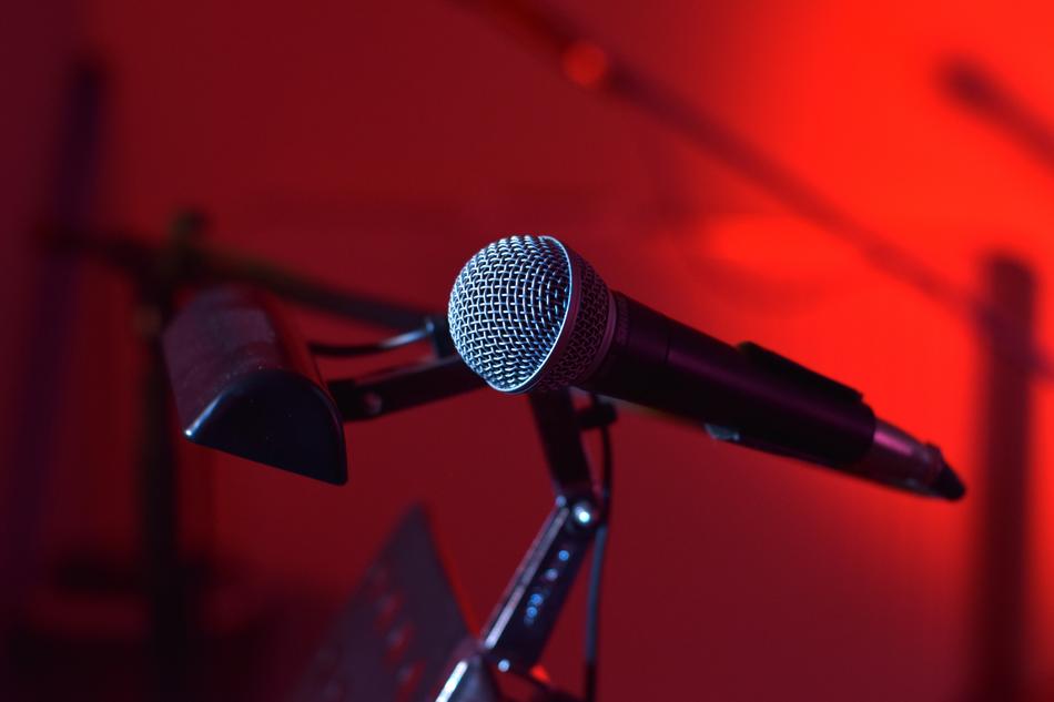 Close-up of the beautiful, grey microphone in light, on the stage, at background with red light