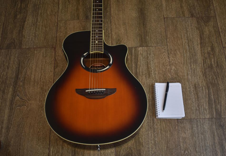 Songwriting, pen on notebook near guitar