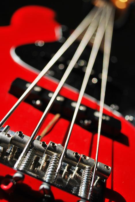 Close-up of the shiny strings, of the red jazz guitar