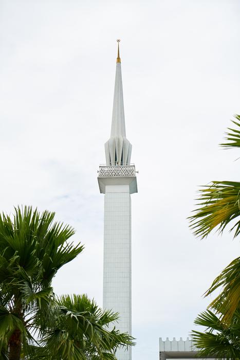 Beautiful, white minaret of the cami, among the palm trees, in Malaysia