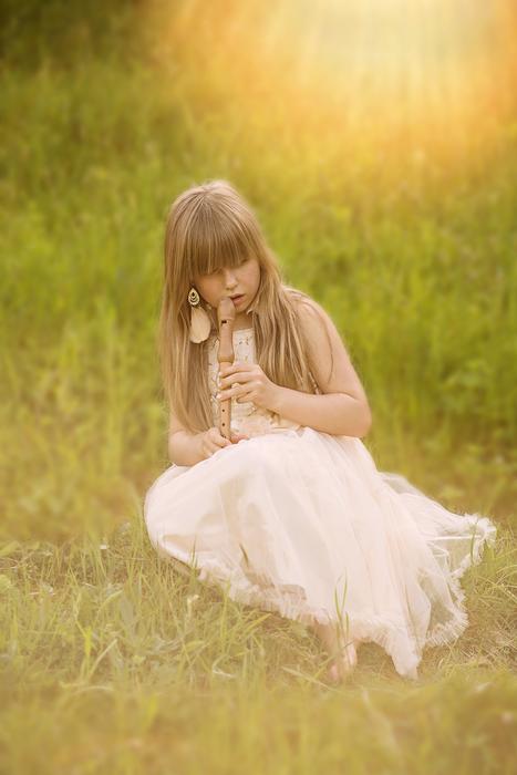 girl with a flute on the grass in the sunlight