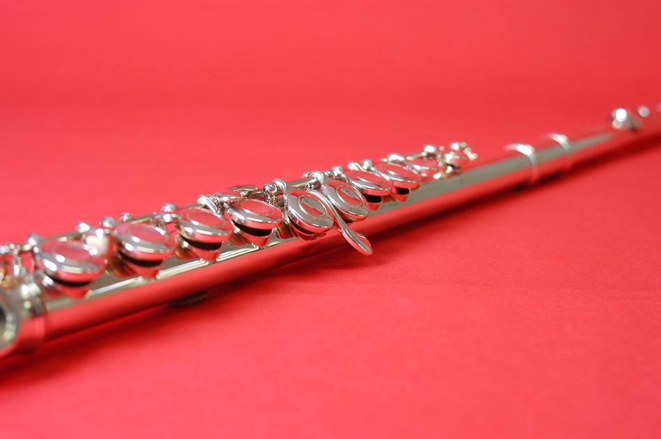 Close-up of the beautiful, glossy, silver flute, on the red surface