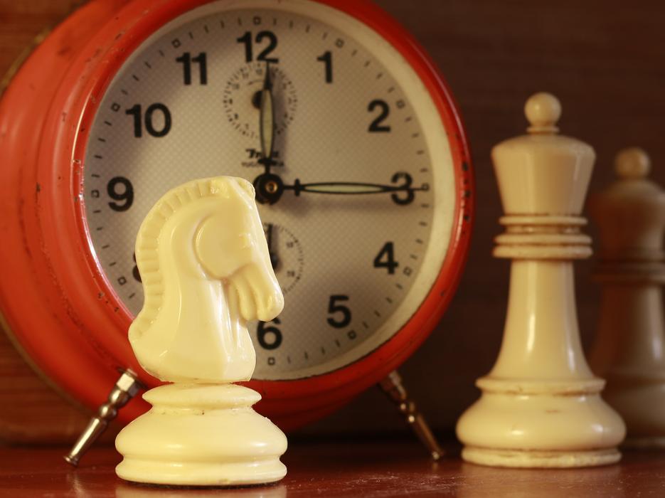 chess pieces on the background of the alarm clock