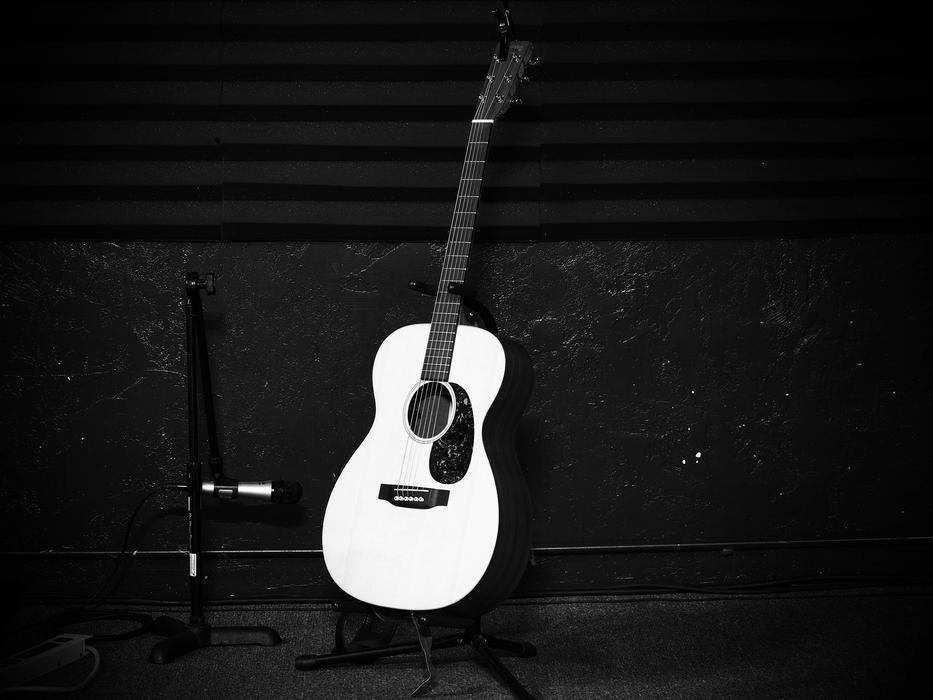 Black and white photo of the beautiful guitar near the black wall
