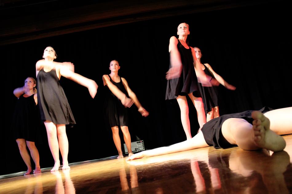 Girl dancers in black dresses, on the beautiful stage in light