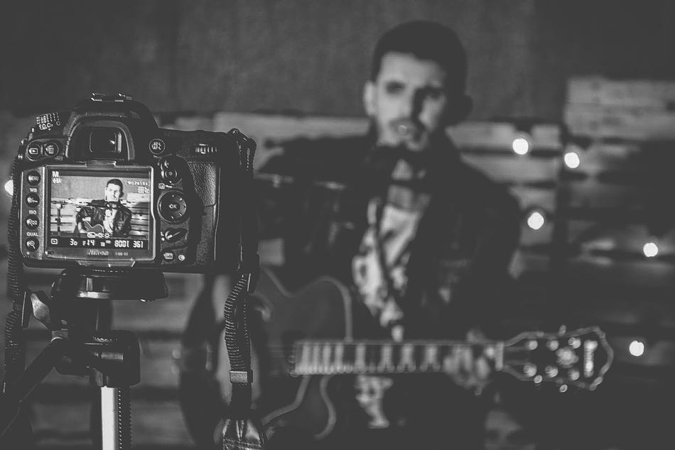 man plays Guitar in front of photo camera