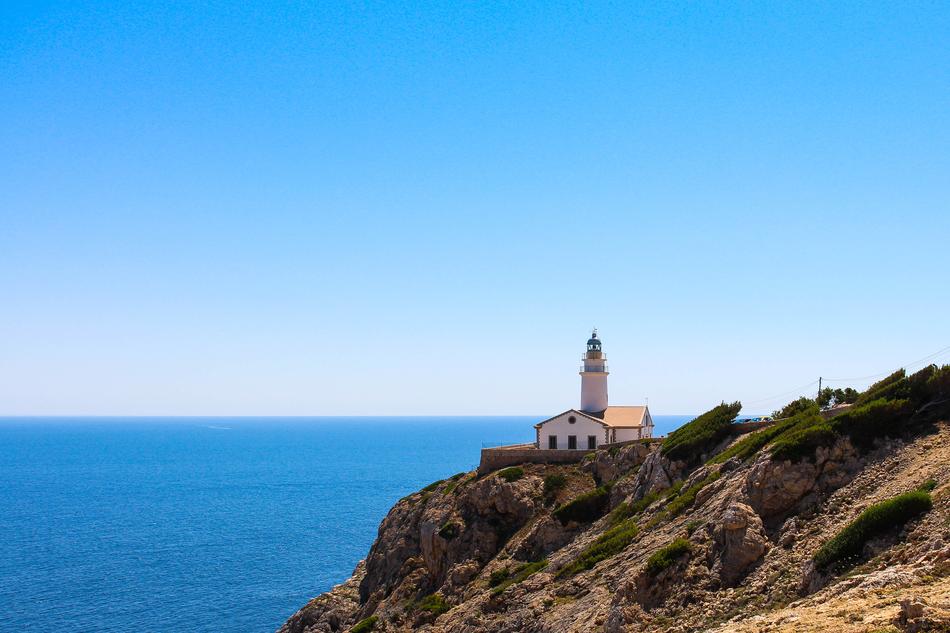 Beautiful rocky coast of the Belearic Islands with the lighthouse, anibg the blue water in Spain
