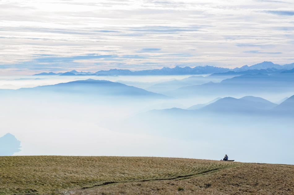 Beautiful and colorful panorama of the mountains, in clouds, from the Monte Lema, Switzerland, with the person