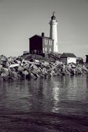 old lighthouse on rock at sea, black and white