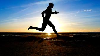 silhouette of muscular runner at sunset