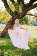 young girl in long Wedding dress beneath tree