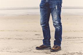 blue jeans on a man standing on a sand