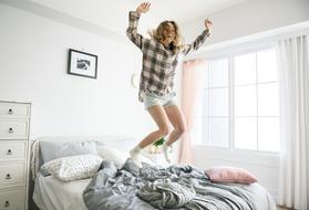happy young girl jumps on bed