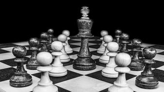 Black and white photo of the chessboard, with the beautiful chess pieces, at black background