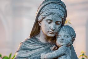 Stone sculpture figure of the mother with the child on blurred background