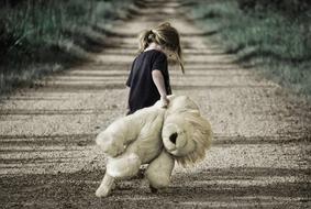 little girl with teddy on the road