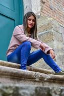 Young woman sits on stone steps at door